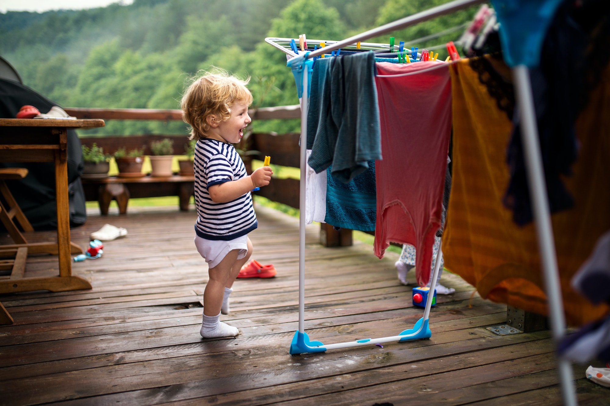 Toddler children outdoors in summer, playing with clothes drying hanger.